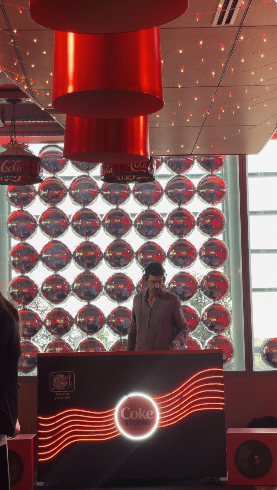 Pedro Etcheverry musicalizando en cabina de Coke Studio en las oficinas de Coca-Cola, con pared de globos rojos y plateados