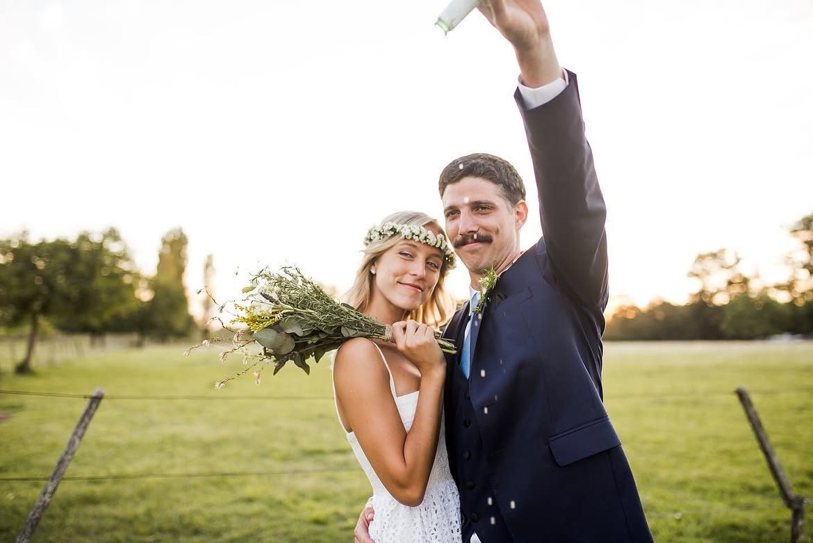 Novios celebrando con el ramo entre confeti en su casamiento al aire libre