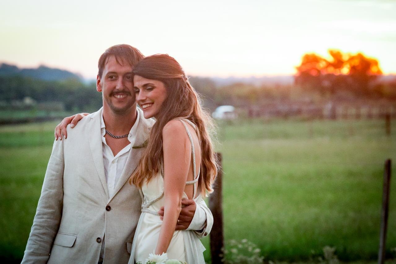 Pareja de novios abrazados al atardecer en casamiento al aire libre