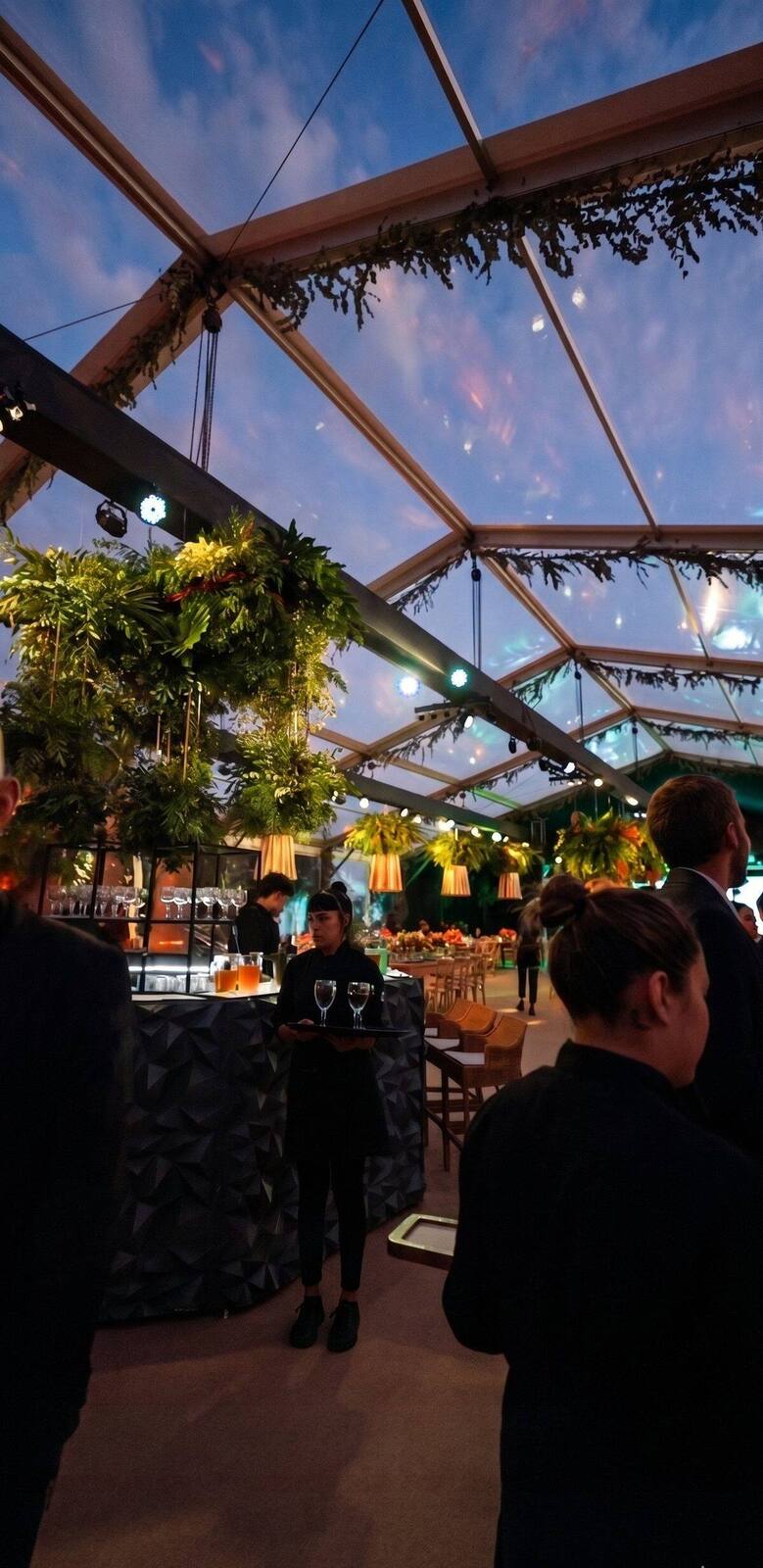 Recepción al aire libre con pérgola, faroles y luz cálida en evento de casamiento al atardecer